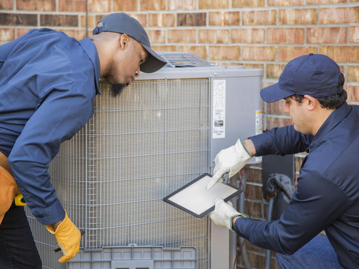 Two workers repair HVAC equipment