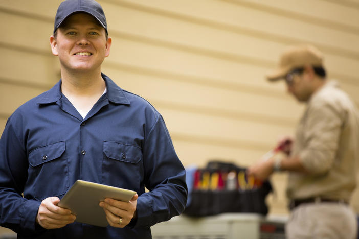 HVAC contractor holds tablet device